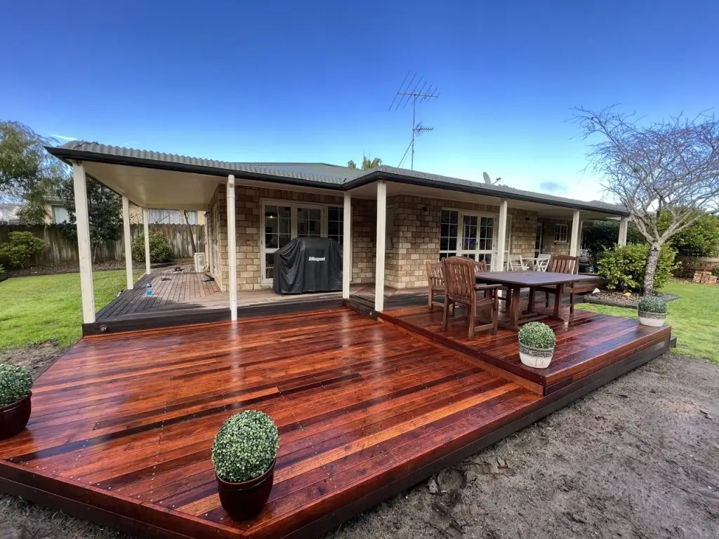 Minimalist dining and kitchen space styled by Visionary Outdoor Solutions with wooden furniture and large windows