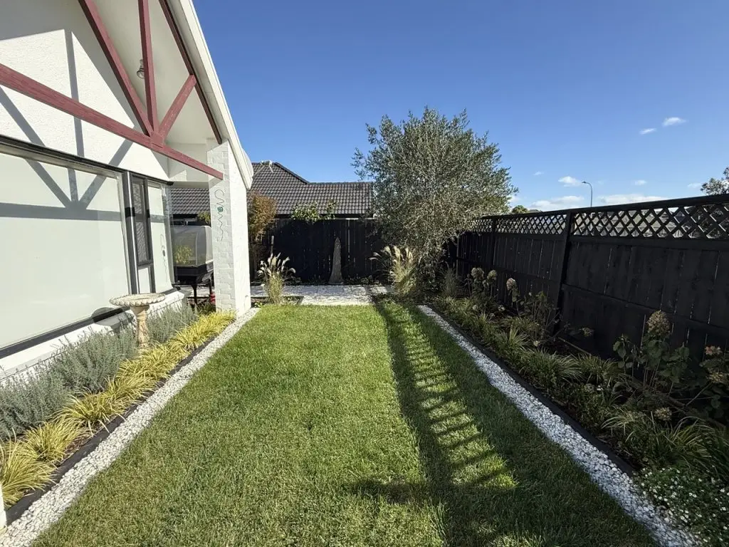 Contemporary outdoor garden patio with lawn and lush greenery designed by Visionary Outdoor Solutions